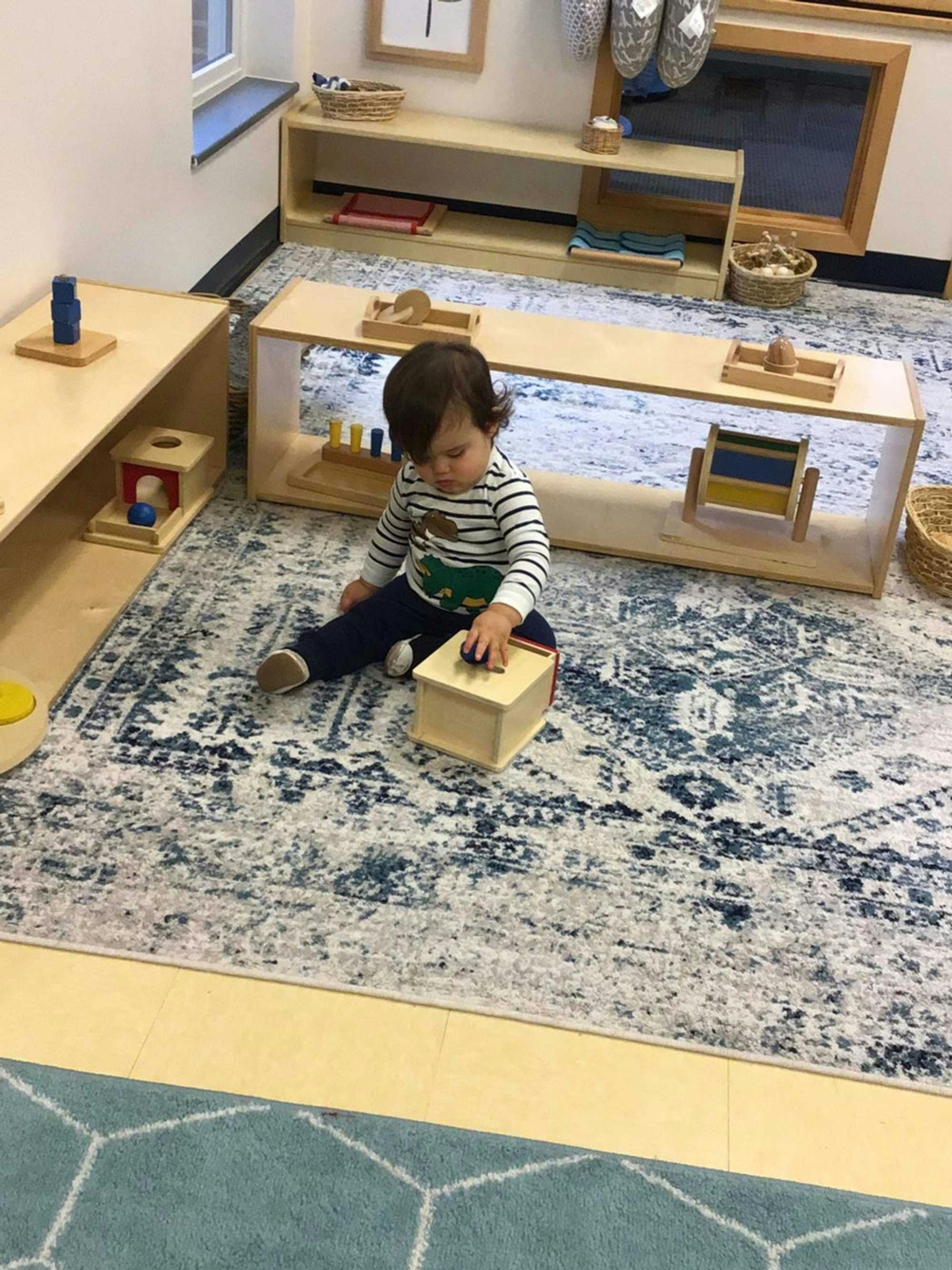 Children in a well-organized mixed-age Montessori classroom ponder over an activity using blocks of different sizes, classic Montessori classroom materials