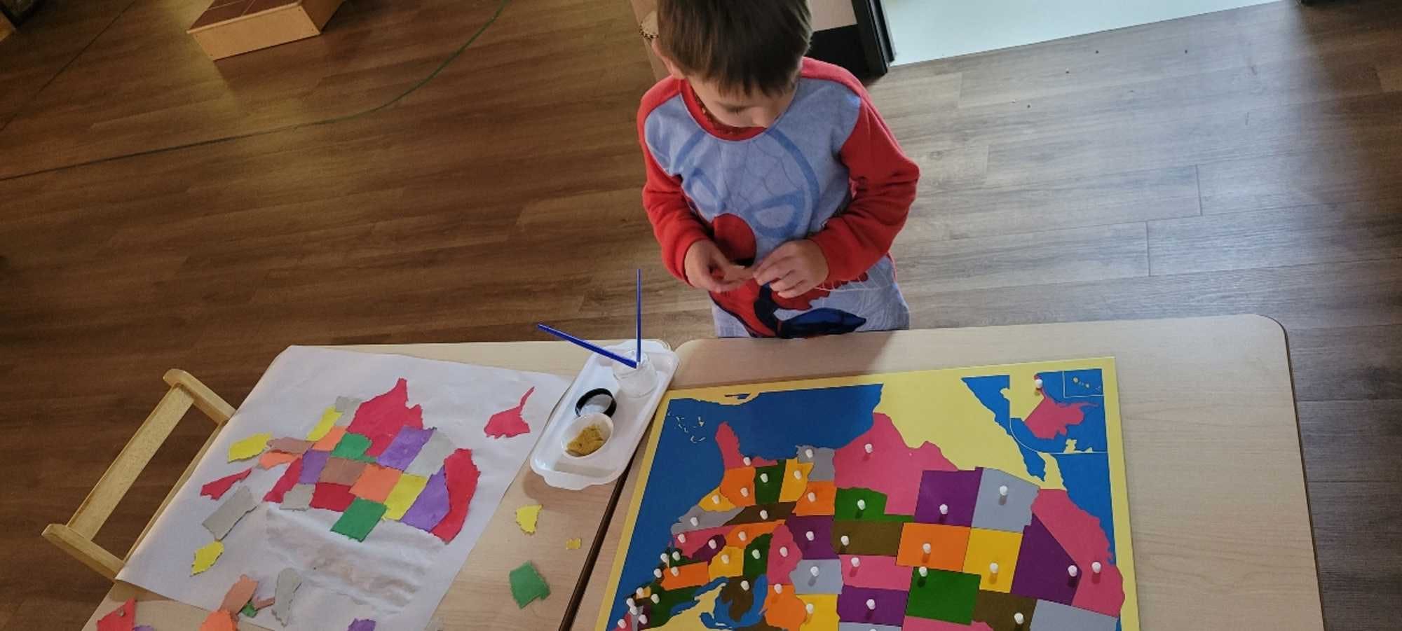 kindergarten-aged boy enjoys playing with map of the U.S in the well-organized Montessori classroom. 